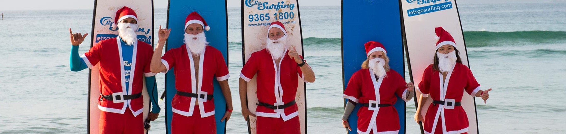 people dressed as santa holding a surfboard