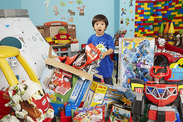 Ryan looking at camera surrounded by toys