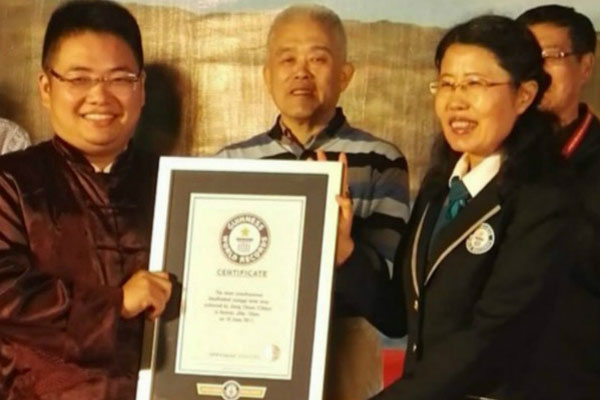 Xiangqi holding his certificate next to adjudicators