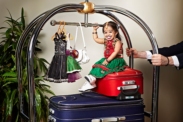 jyoti sitting on top of small red suitcase
